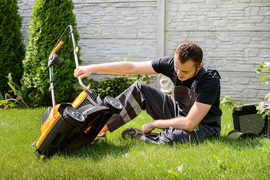 Person repariert Rasenmäher